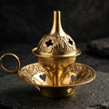 Brass cone incense burner on dark slate