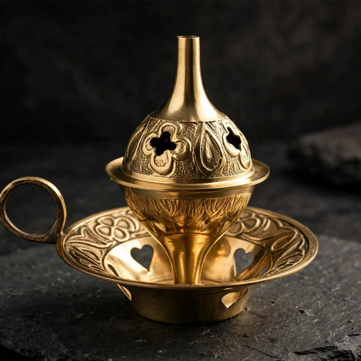 Brass cone incense burner on dark slate