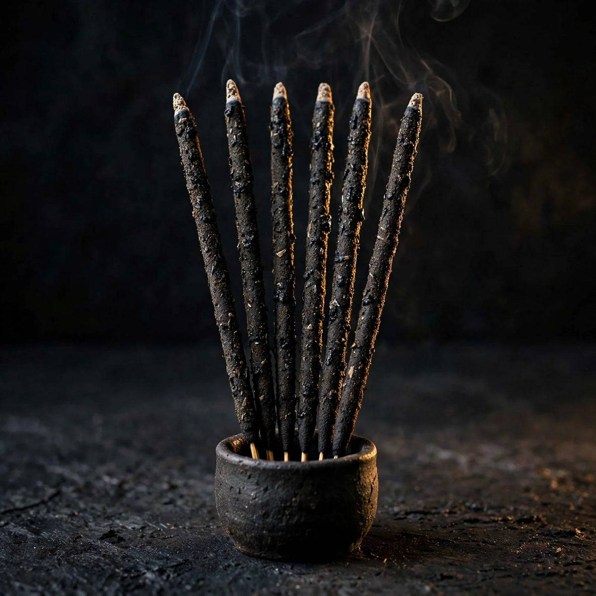 Six hand-rolled black copal incense sticks on dark background